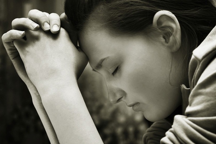 woman head bowed, eyes closed in prayer